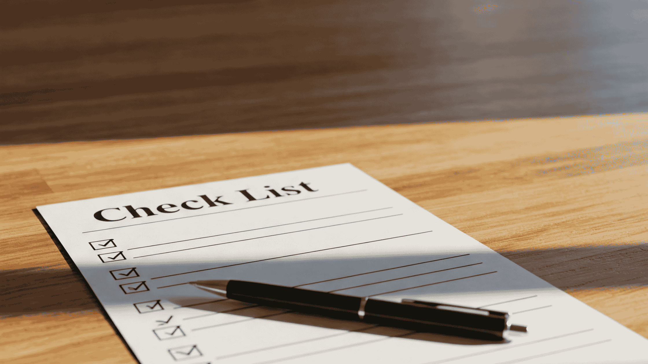 木製テーブル上の「Check List」とペン。自己分析を連想させる。